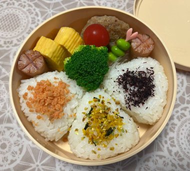 Geleneksel bir Kore dozirak 'ı. Pirinç, çeşitli banchan ve tuzlu proteinlerle güzelce düzenlenmiş. Dengeli ve görsel olarak davetkâr, canlı lezzetlerle dolu taşınabilir bir yemek..