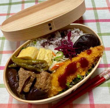 Geleneksel bir Kore dozirak 'ı. Pirinç, çeşitli banchan ve tuzlu proteinlerle güzelce düzenlenmiş. Dengeli ve görsel olarak davetkâr, canlı lezzetlerle dolu taşınabilir bir yemek..