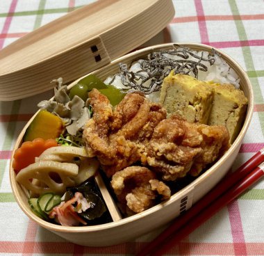 Geleneksel bir Kore dozirak 'ı. Pirinç, çeşitli banchan ve tuzlu proteinlerle güzelce düzenlenmiş. Dengeli ve görsel olarak davetkâr, canlı lezzetlerle dolu taşınabilir bir yemek..