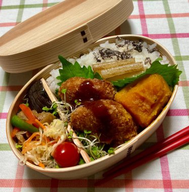 Geleneksel bir Kore dozirak 'ı. Pirinç, çeşitli banchan ve tuzlu proteinlerle güzelce düzenlenmiş. Dengeli ve görsel olarak davetkâr, canlı lezzetlerle dolu taşınabilir bir yemek..