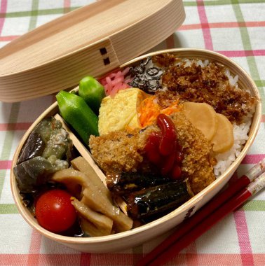 Geleneksel bir Kore dozirak 'ı. Pirinç, çeşitli banchan ve tuzlu proteinlerle güzelce düzenlenmiş. Dengeli ve görsel olarak davetkâr, canlı lezzetlerle dolu taşınabilir bir yemek..