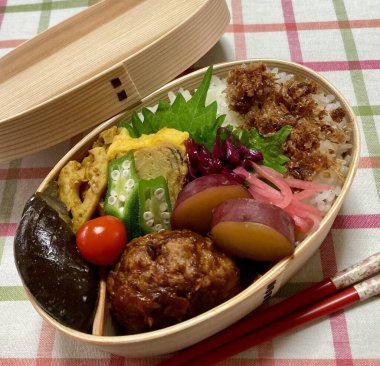 Geleneksel bir Kore dozirak 'ı. Pirinç, çeşitli banchan ve tuzlu proteinlerle güzelce düzenlenmiş. Dengeli ve görsel olarak davetkâr, canlı lezzetlerle dolu taşınabilir bir yemek..