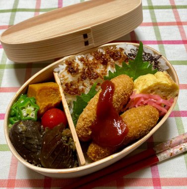 Geleneksel bir Kore dozirak 'ı. Pirinç, çeşitli banchan ve tuzlu proteinlerle güzelce düzenlenmiş. Dengeli ve görsel olarak davetkâr, canlı lezzetlerle dolu taşınabilir bir yemek..