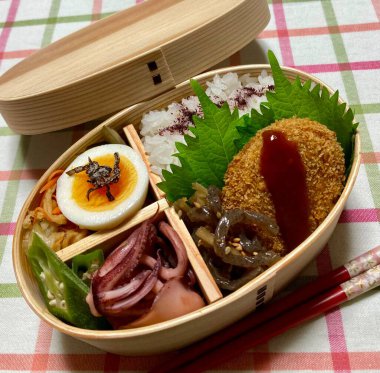 Geleneksel bir Kore dozirak 'ı. Pirinç, çeşitli banchan ve tuzlu proteinlerle güzelce düzenlenmiş. Dengeli ve görsel olarak davetkâr, canlı lezzetlerle dolu taşınabilir bir yemek..