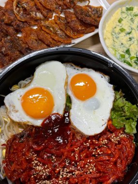 Yukhoe bibimbap taze sebzeler, pilav, baharatlı çiğ biftek, çiğ yumurta sarısı ve Gochujang klasik bir Kore yemeği içinde kalın bir lezzet ve doku karışımı sunar..