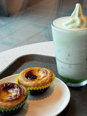 Hoş bir kafe ortamında sergilenen tatlı çeşitleri zarif tabaklar üzerinde pastalar, pastalar ve tatlı ikramlar, sıcak ve davetkar bir atmosfer yaratıyor..