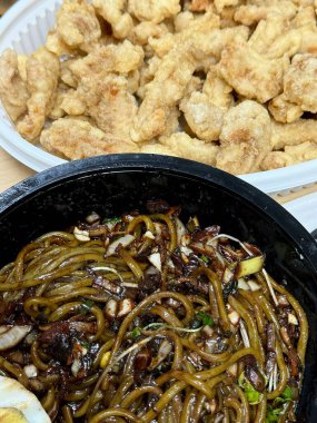 Zengin siyah fasulye sosuna bulanmış kalın, çiğnenmiş erişteli klasik Kore-Çin karışımı, yanında gevrek tangsuyuk, bol yağda kızartılmış domuz eti ve tatlı ve ekşi sos servis edilir..