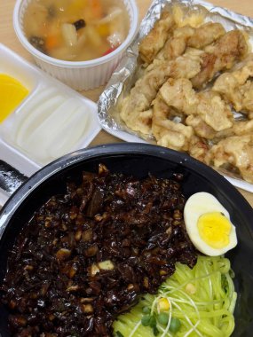 Zengin siyah fasulye sosuna bulanmış kalın, çiğnenmiş erişteli klasik Kore-Çin karışımı, yanında gevrek tangsuyuk, bol yağda kızartılmış domuz eti ve tatlı ve ekşi sos servis edilir..