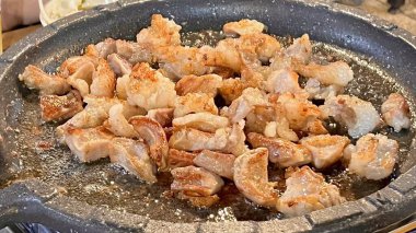 Izgara samgyeopsal, kalın domuz eti dilimleri çıtır çıtır ve taze et. Klasik bir Kore barbekü deneyimi için marul, sarımsak ve sosla servis ediliyor..