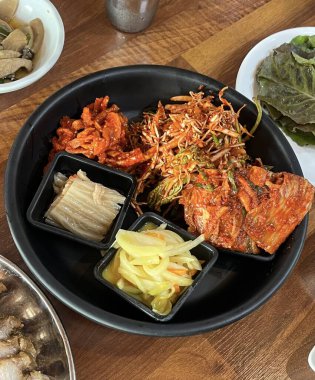 İçinde kimchi, baharatlı sebze, turp turşusu ve marine edilmiş yosun bulunan renkli bir banchan çeşidi. Bu Kore mezeleri masaya çeşitli dokular ve tatlar getiriyor..