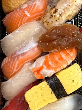 Çeşitli malzemeler ve canlı renklerle sanatsal olarak düzenlenmiş taze suşi çeşitleri. Bu geleneksel Japon yemeği bir deneyim için sirkeli pirinç, deniz ürünleri ve sebzeleri birleştirir..