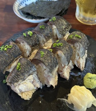 Çeşitli malzemeler ve canlı renklerle sanatsal olarak düzenlenmiş taze suşi çeşitleri. Bu geleneksel Japon yemeği bir deneyim için sirkeli pirinç, deniz ürünleri ve sebzeleri birleştirir..