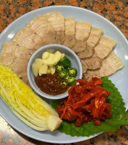 Yumuşak bir parça Bossam, Kore haşlanmış domuz göbeği, taze marul, sarımsak ve ssamjang ile servis edilir. Bu lezzetli ve lezzetli yemek geleneksel bir Kore yemeğini paketlemek ve paylaşmak için mükemmeldir..