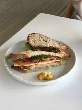 Marul, domates, peynir ve meze gibi taze malzemelerle dolu lezzetli bir sandviç. Hepsi de iki dilim yumuşak ekmeğin arasına istiflenmiş. Hızlı ve tatmin edici bir yemek için mükemmel..