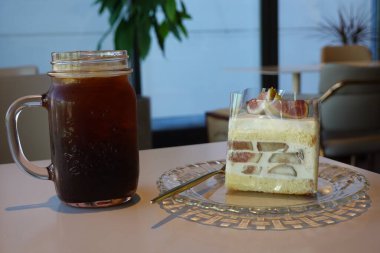 Nemli ve aromalı kek dilimleri cesur, ferahlatıcı bir buz americano ile eşleştirilir, tatlı hoşgörü mükemmel bir ahenk sunar ve her nefis kafe tarzı ısırma ve yudumlama için zengin kahve derinliği.