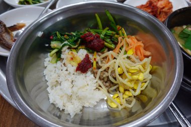 Yukhoe bibimbap taze sebzeler, pilav, baharatlı çiğ biftek, çiğ yumurta sarısı ve Gochujang klasik bir Kore yemeği içinde kalın bir lezzet ve doku karışımı sunar..