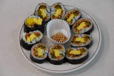 Taze sebzelerle, baharatlı pirinçlerle ve gevrek yosunlara sarılmış lezzetli proteinlerle dolu nefis kimbap dürümleri. Her ısırıkta lezzet ve dokuların mükemmel bir kombinasyonu.