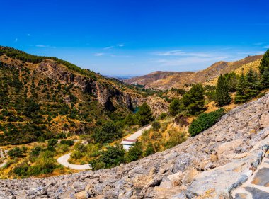 View from Behind Canales Dam Overlooking Rugged Terrain and the Genil River in Granada, Spain clipart