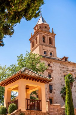 Alhambra Bahçeleri 'ndeki Santa Maria Tarihi Kilisesi' nin Yükselen Çan Kulesi. Çerçevesi Lush Cypress, Blooming Yeşillikleri ve Azure Endülüs Gökyüzü tarafından çevrilmiş.