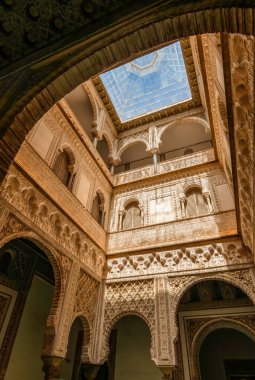 Intricate Moorish Filigree and a Sunlit Glass Ceiling in the Patio de las Muecas The Royal Alczar of Sevilles Exquisite Mudejar Masterpiece clipart