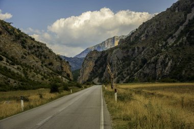 Arnavutluk 'un güneybatısına uzanan Rruga e Permetit (Permet Yolu), engin bir gökyüzü altında yüksek kireçtaşı tepeleri ve altın çayırlarla çevrelenmiş durumda.