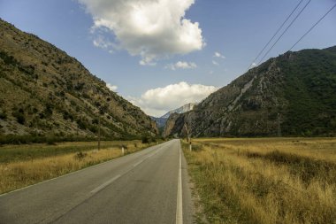 Arnavutluk 'un güneybatısına uzanan Rruga e Permetit (Permet Yolu), engin bir gökyüzü altında yüksek kireçtaşı tepeleri ve altın çayırlarla çevrelenmiş durumda.