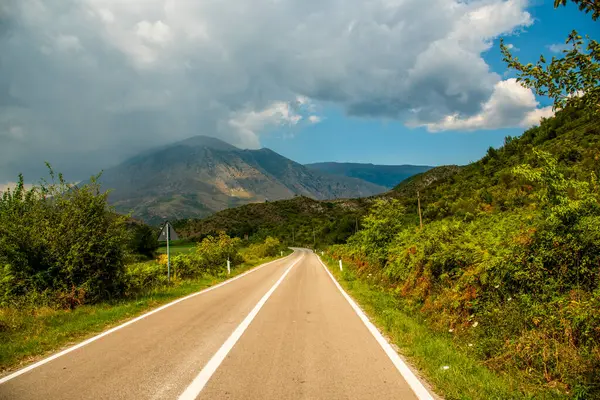 The road to Permet weaves through southwestern Albanias lush valleys and looming peaks, promising a scenic Balkan journey under shifting cloud cover
