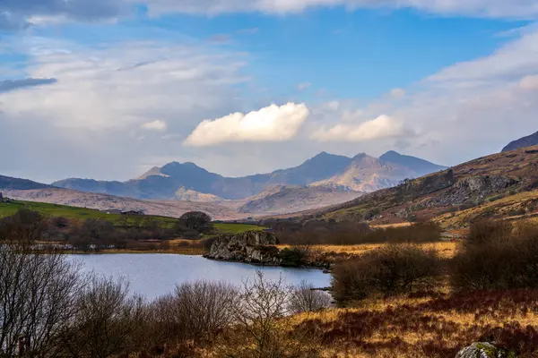Snowdonias Llyn Gwynant reflects a majestic mountain panorama under a vibrant Welsh sky, capturing serene beauty in North Wales.