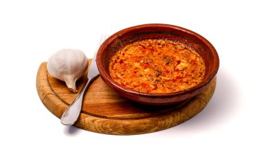 A steaming Tav Dheu served in a rustic clay pot, paired with fresh garlic on a wooden board, celebrating hearty Albanian tradition