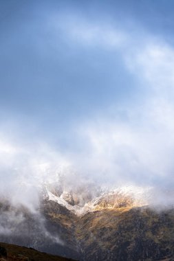 Glyderau 'da yer değiştiren sis battaniyeleri hafif kar ile taçlandırılmış yükselen Galler zirvelerinin kısa görüntülerini gözler önüne seriyor.