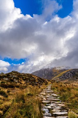 Kuzey Eryri 'de Llyn Idwal' a doğru sert bir patika esiyor, maceraperestleri düşüncelere dalan zirveler ve açık kayak sözcükleriyle yükselmeye çağırıyor (toplamda 50, virgülle ayrılmış)):