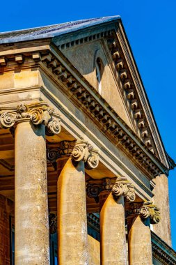 Volt başkentleriyle Neoklasik İyonik Portico ve Bulutsuz mavi gökyüzüne karşı Altın Faade 'de Denny Cornice
