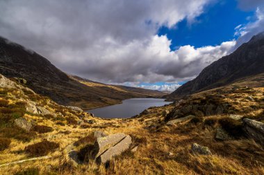 Sakin buzul tarn Llyn Idwal kayan bir bulutun altında engebeli tepe ve kehribar tussock arasında yuvalanmış