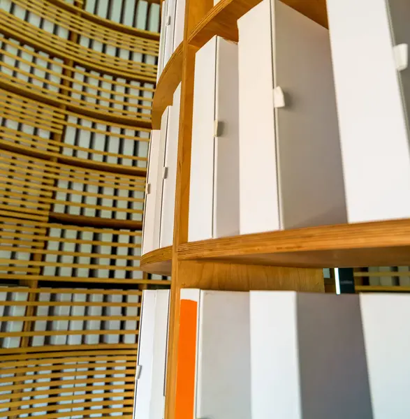 Yuvarlak huş ağacından yapılmış raflara düzgünce dizilmiş beyaz arşiv dosyalarının yakın çekimi, eğri ahşap bir zemin zeminine karşı.