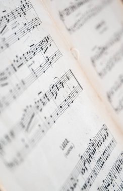 Yaşlanmış piyano notalarının makro yakın plan görüntüleri canlı müzik notalarını ve yumuşak bulanık kenarlı dokuma kağıtlarını ortaya çıkarıyor.