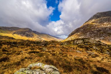 Cwm Idwal 'ın kayan bulutların altındaki engebeli granit kayalıklarla çerçevelenmiş fundalıklı corrie havzası.