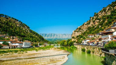 Tarihî Osmanlı evleri ve Berat 'ın terasotta çatıları kireçtaşı kayalıklardan Osum Nehri üzerindeki taş kemerli bir köprüye dökülüyor berrak bir gökyüzünün altında