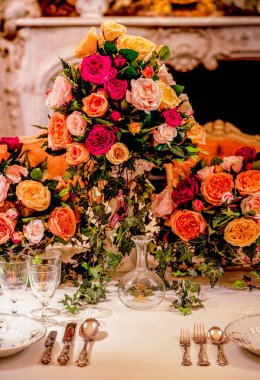 Görkemli mercan, pembe ve şeftali bahçesi gülleri sarmaşıklarla sarmalanmış sıcak mum ışığında zarif bir ziyafet masası süslüyorlar.