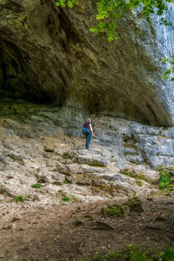 Dovedale 'in Tepe Bölgesi' ndeki Görkemli Mağara Girişleri 'ni araştırıyorum. Kireçtaşı oluşumlarına karşı ayakta duran bir yürüyüşçü.