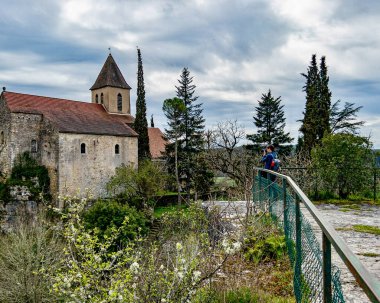 woman photographer capturing historical stone church of Calvignac  clipart