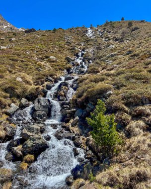 Şelale gibi akan dere berrak gökyüzü ile kayalık dağ arazisinde akar.