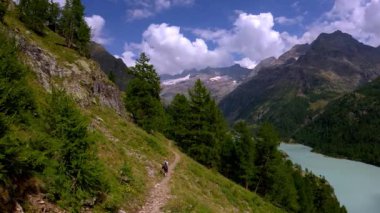 Turkuaz yer Moulin Gölü İtalyan Alpleri üzerinde dar bir patika üzerinde yürüyüşçü.