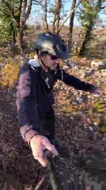 Bahar Ormanı 'nda engebeli arazi ve yapraklarla tek tekerlekli bisiklet süren bir adam.