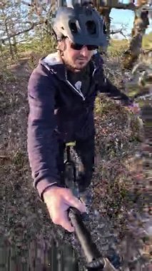 Miğferli Adam Yapraksız Ormanlık yamaçta Tek Bisiklet Sürüyor