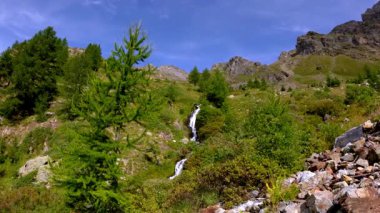 Parlak mavi gökyüzünün altında Bionaz, Aosta Vadisi 'nin yakınlarındaki el değmemiş doğal ortamda taze alp şelalesi.