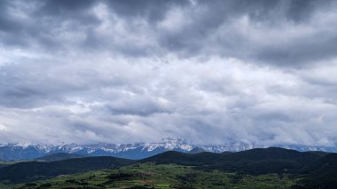 Serra del Cad dağlarını, Cerdanya vadisi, Katalonya ve Spai 'nin yeşil tarımsal ovalarına bakan fırtınalı bahar gökyüzünün altında karla kapladı.