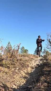 Yavaş çekimde yetenekli tek tekerlekli bisikletçi Akdeniz kırsalındaki kırsal Fransız kırsalında yokuş aşağı giden taşlı patikada geziniyor.