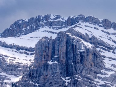 breathtaking capture Roca Verda colossal stone presence in the Pyrenees, its snow dusted contours rising majestically under an atmospheric brooding winter sky revealing raw beauty.