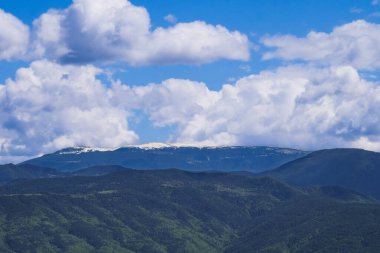 Pofuduk beyaz bulutların, verimli, dokulu yeşil yamaçların tepelerinde karla kaplı tepeleri taçlandırdığı Pireneler 'in sanatsal çizimi.