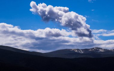 Geniş ve dinamik dağ manzarası engebeli zirveler ve güçlü bulut oluşumları, açık hava macerası ve seyahat promosyonları için mükemmel.